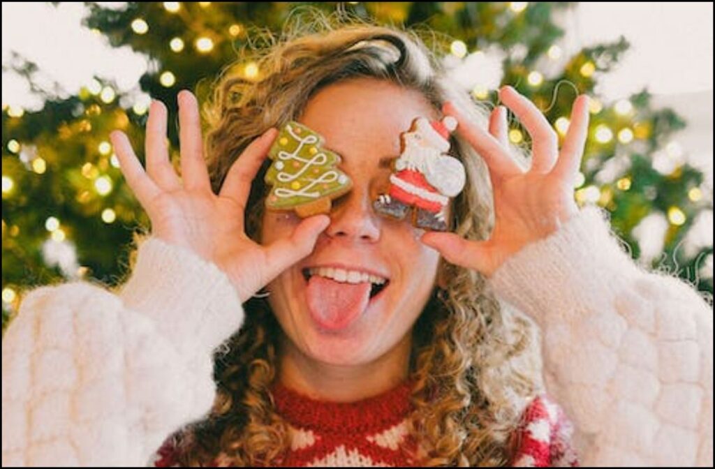 A girl holding Christmas cookies near her eyes