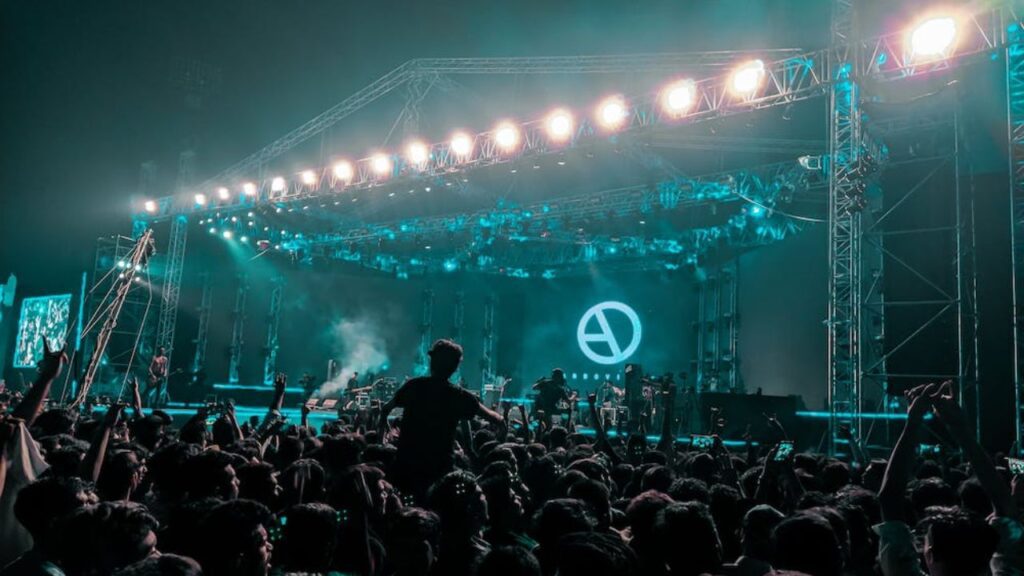 picture of a music concert with a band performing and many audience dancng