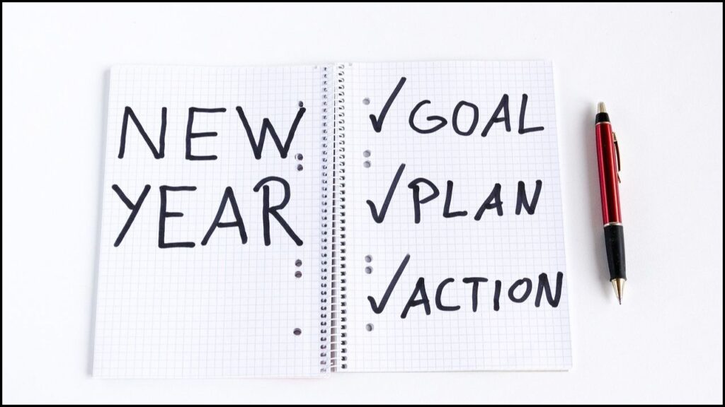 spiral binded book for new year resolution with checklists of goal, plan, action a pen aside