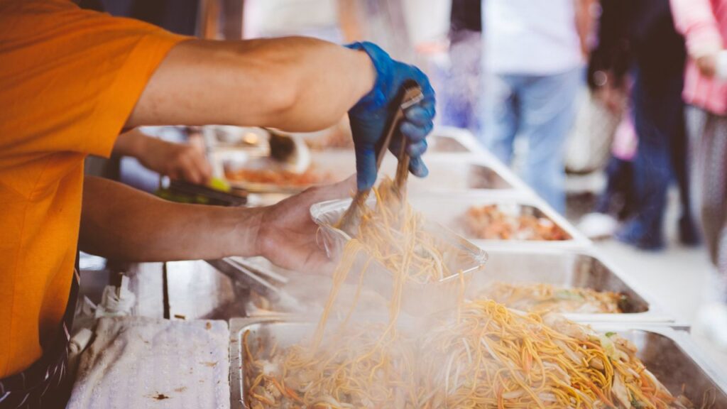 a street food vendor packing noodles in an aluminum packing box