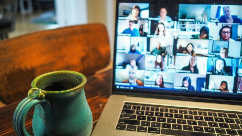 image of a cup and a laptop in which a group of people having video conference