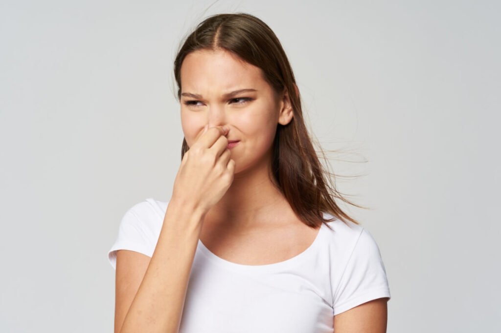 An image of a woman closing her nose with hands because of bad odor