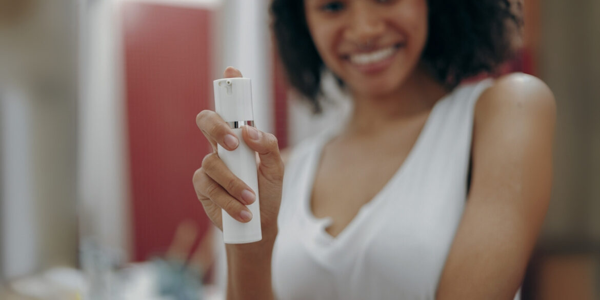 An image of a woman with a body spray in her hand