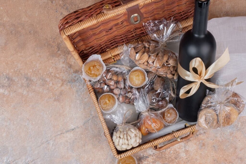 An image of a gift box with dried fruits, nuts and a wine bottle.