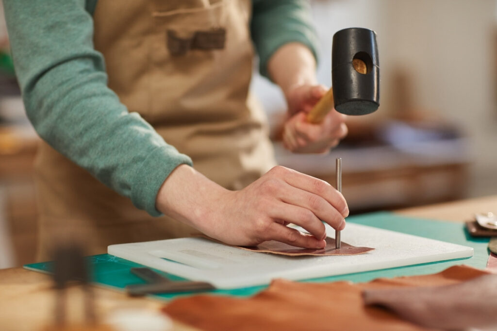 An image of A man hammering over a leather patch