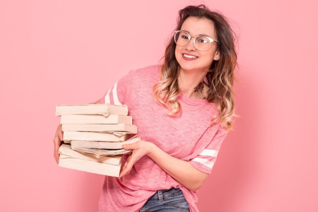 An image of a woman with a pile of books in her hand