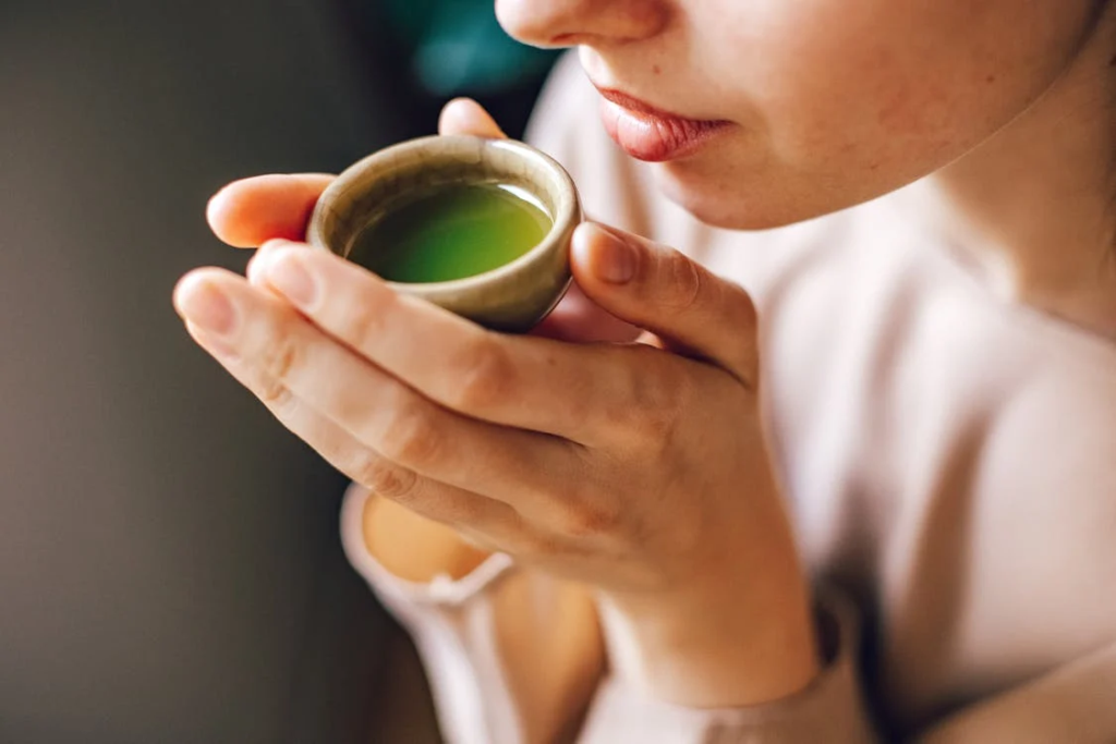 Is Matcha the New Perfume Trend? 18 A person's hands carefully hold a small cup of bright green matcha tea as they bring it to their lips.
