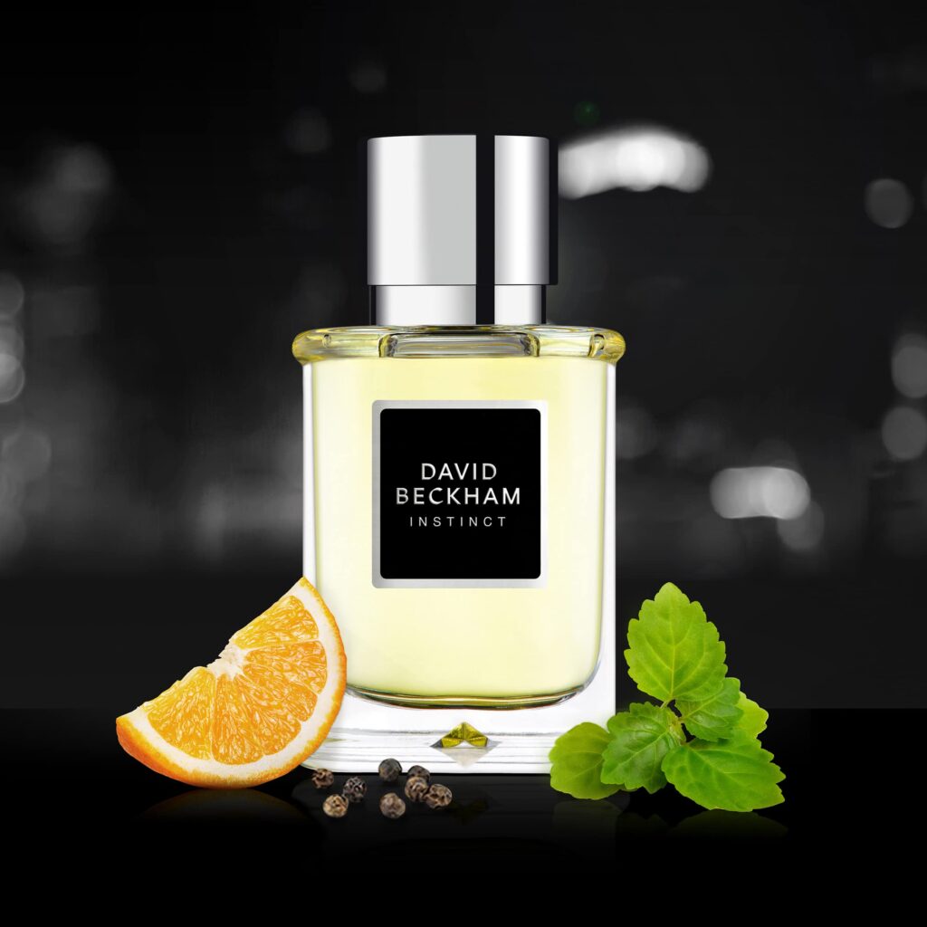 5 Football Stars Who Won the Fragrance Game 26 In this image David Beckham Instinct Eau de Toilette bottle displayed against a blue background, surrounded by visual representations of its fragrance notes: zesty bergamot, juicy mandarin orange, aromatic star anise, spicy pimento, warm cardamom, earthy patchouli, smoky vetiver, and smooth white amber, capturing the fresh and masculine essence of the scent.