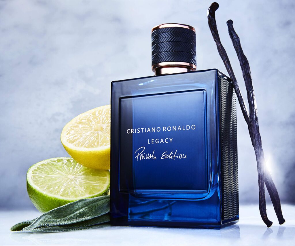 5 Football Stars Who Won the Fragrance Game 24 In this image Cristiano Ronaldo Legacy Private Edition Eau de Parfum bottle displayed against a blue background, surrounded by visual representations of its fragrance notes: sweet maple syrup, fresh neroli, aromatic basil, warm tonka bean, creamy sandalwood, rich cedar, smooth vanilla, golden amber, earthy moss, and sensual musk, encapsulating the luxurious and bold essence of the scent.
