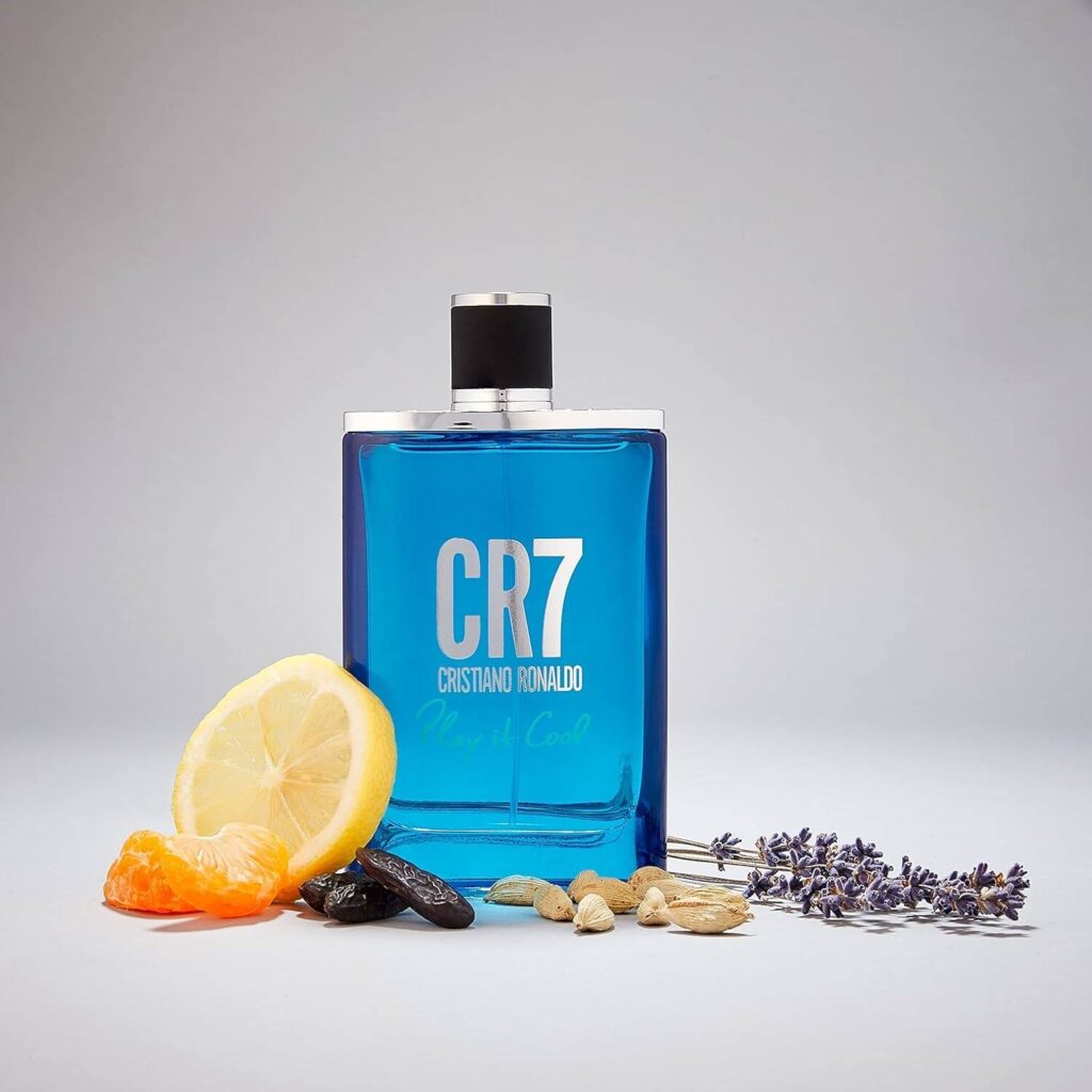 5 Football Stars Who Won the Fragrance Game 23 In this Image CR7 Play It Cool Eau de Toilette bottle displayed against a blue background, surrounded by visual representations of its fragrance notes: juicy mandarin orange, crisp pear, zesty bergamot, refreshing sea notes, aromatic lavender, spicy cardamom, warm tonka bean, rich amber wood, and sensual musk, capturing the fresh and invigorating essence of the scent.