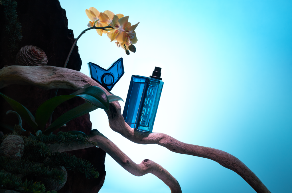 5 Football Stars Who Won the Fragrance Game 19 In this image Messi EDP perfume bottle elegantly displayed against a blue background, surrounded by vibrant visual representations of its fragrance notes: zesty citrus, aromatic lavender, and warm amber, highlighting the essence of its bold and refined scent.