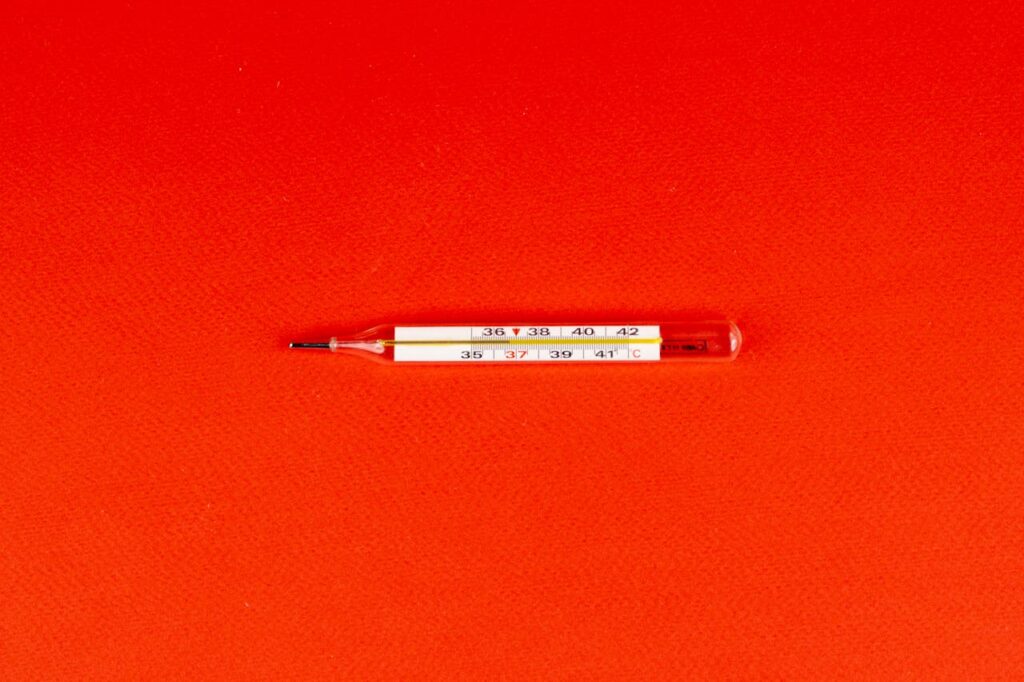 Glass thermometer on a red background showing temperature scale.