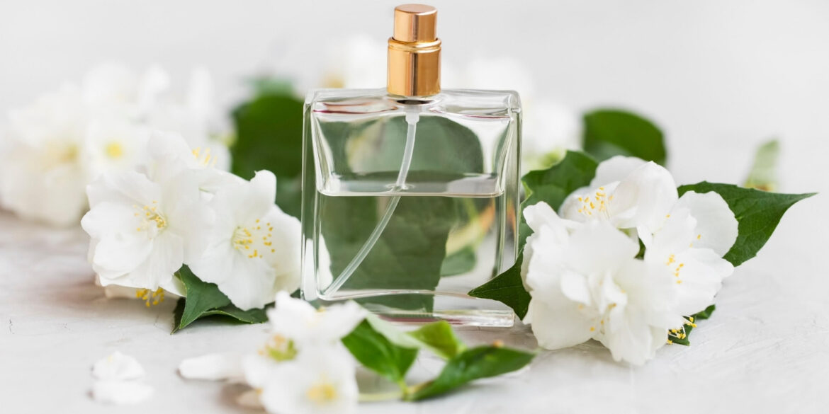 An image of a perfume with jasmine around it