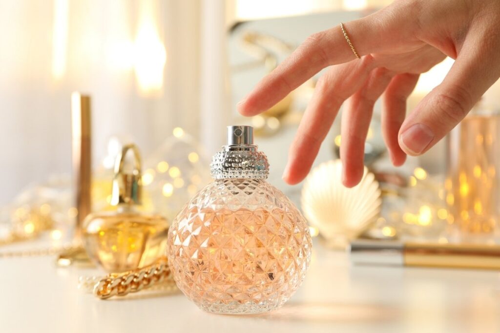 What Really Makes a Perfume Feel Romantic? 20 An image of a luxury perfume bottle with golden ambience and a hand above it