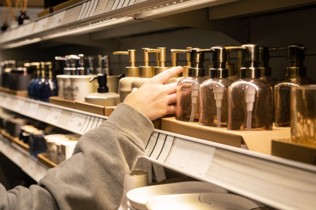 An image of different perfumes in shelves and a woman selecting it