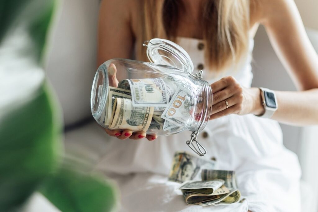 An image of a woman putting money inside a jar