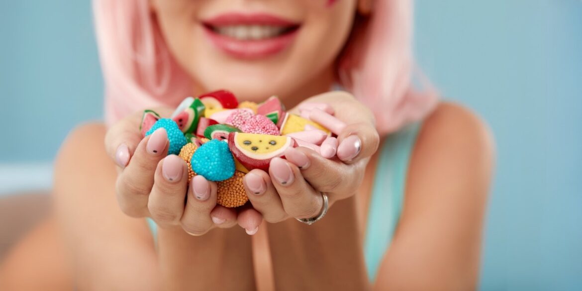 An image of a woman with different kinds of candy and sweets in her hand