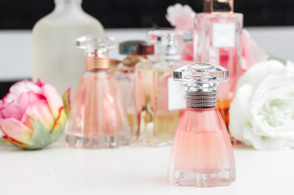 An image of different pefume and flowers placed over a tabletop