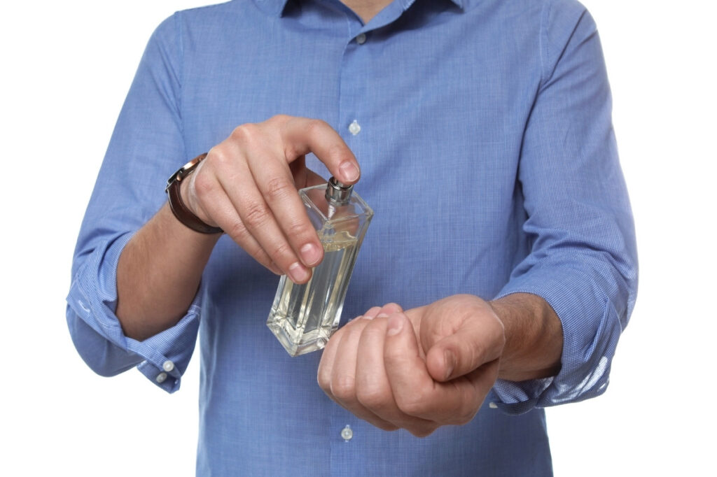 An image of a man applying perfume on the wrist