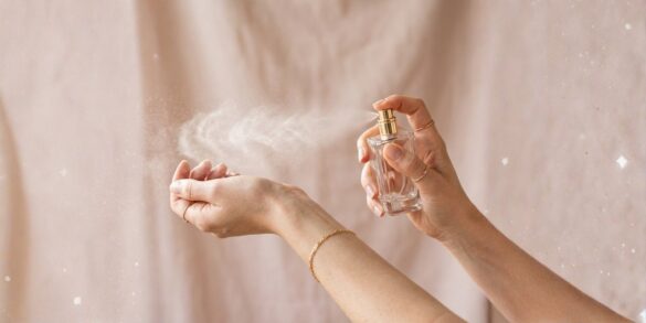 Una imagen de una persona rociándose perfume en la muñeca.